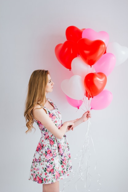 Mädchen im romantischen Kleid mit Ballonen in Form eines Herzens