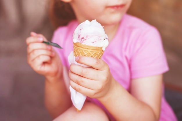 Mädchen im rosa Kleid, das bei heißem Wetter Eis isst