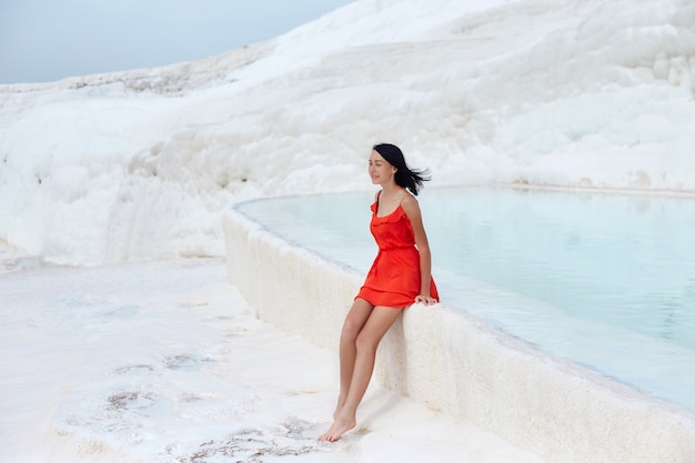 Mädchen im roten Kleid auf weißen Travertinen, Wasser