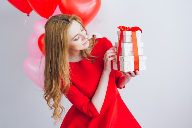 Mädchen im roten Kleid hält Kästen mit Geschenken