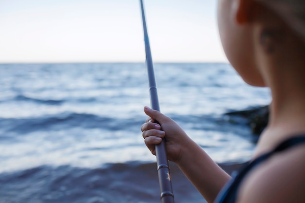 Mädchen im Schwimmen tragen Angeln vom Meeresstrand in den blauen Stunden des frühen Morgens aktives Wochenendcamping