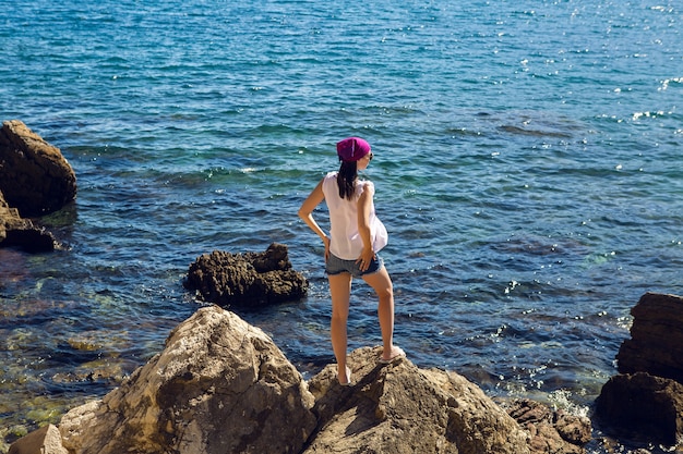 Mädchen im weißen Kleid und in der Sonnenbrille vor dem Meer