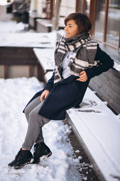 Mädchen im Winter bedeckt im Schal, der durch das Café sitzt