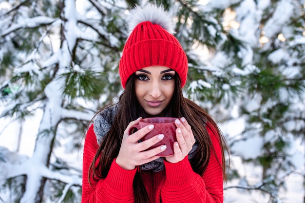 Mädchen im Winterwald mit einer Tasse heißen Tees