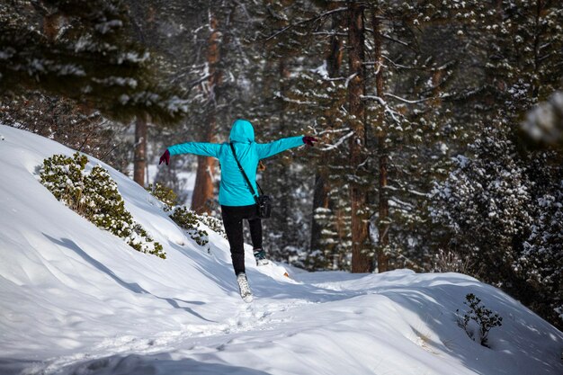 Mädchen in blauer Jacke springt im Winter vor Freude zwischen den mächtigen Felsen des Bryce-Canyon-Nationalparks