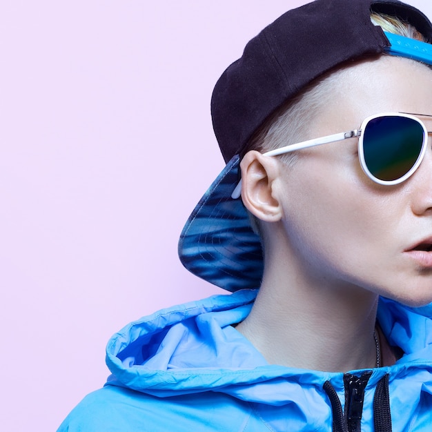 Mädchen in blauer Kleidung und Accessoires. Modische Mütze und Sonnenbrille. Hip Hop Urban Style