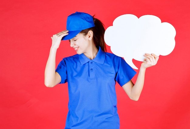 Mädchen in blauer Uniform und Baskenmütze, das ein Denkbrett in Wolkenform hält und müde aussieht und Kopfschmerzen hat.