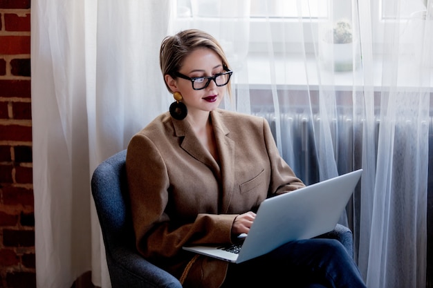 Mädchen in Blazer und Brille arbeiten mit Laptop-Computer