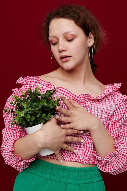 Mädchen in den grünen kurzen Hosen mit einem roten Hintergrund des Blumentopfes unverändert