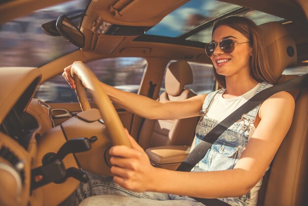 Mädchen in den Sonnenbrillen lächelt beim Fahren des Autos.