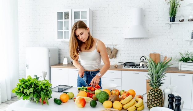 Mädchen in der Küche schneidet Gemüse und Obst