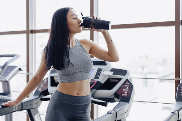 Mädchen in der Turnhalle werden auf Laufband trainiert und trinken Wasser