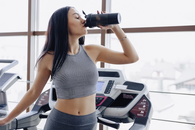 Mädchen in der Turnhalle werden auf Laufband trainiert und trinken Wasser
