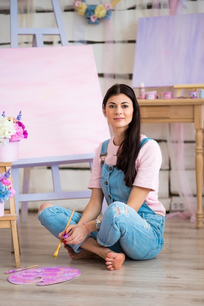 Mädchen in einem blauen Jeansoverall malt im Raum