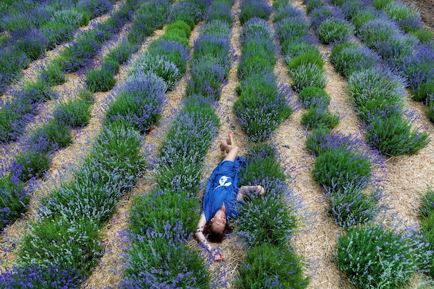 Mädchen in einem blauen Kleid werden in lila Lavendelblüten auf einem Feld fotografiert