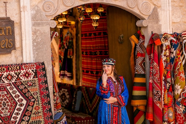 Mädchen in einem blauen nationalen türkischen Kostüm Fotografiert in einem Teppichgeschäft