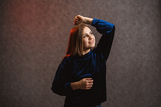 Mädchen in einem blauen Pullover auf grauem Hintergrund. Habe schöne Haare und sie posiert wunderschön