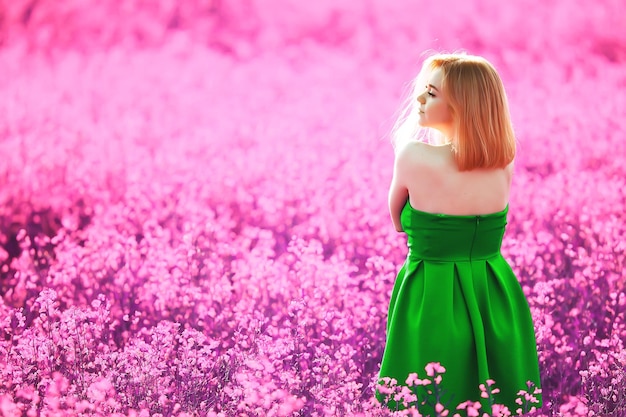 Mädchen in einem Feld von lila Blumen in Lavendelfarben, violette und rosafarbene Landschaft, glücklich und Harmonie