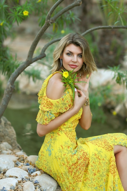 Foto mädchen in einem gelben kleid mit gelben blumen im park