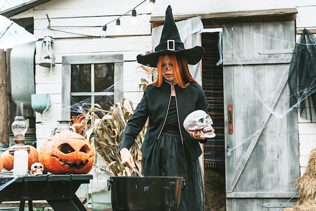 Mädchen in einem Hexenkostüm auf einer Halloween-Party brauen einen Trank