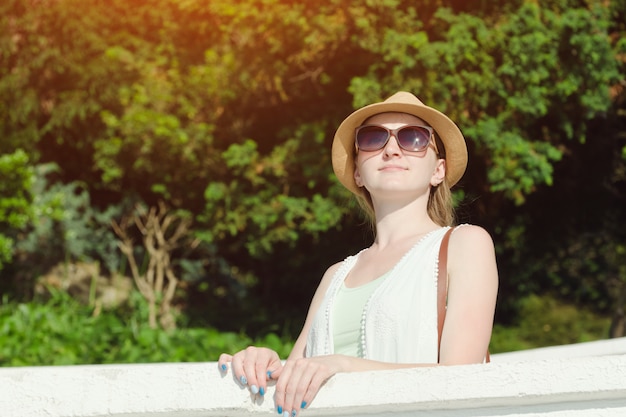 Mädchen in einem Hut mit Sonnenbrille Natur genießend. Sonniger Tag, Park