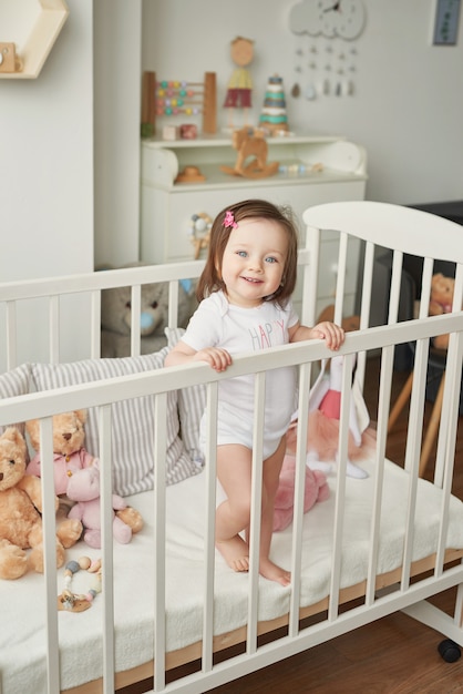 Mädchen in einem Kinderbett mit Spielzeug im Kinderzimmer