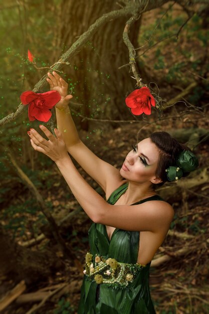 Mädchen in einem Kleid aus grünen Palmblättern an einem Waldsee