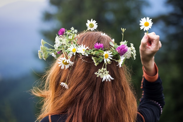 Mädchen in einem Kranz von Wildblumen in den Bergen.