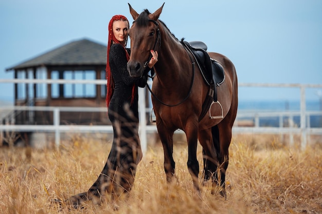 Mädchen in einem langen Kleid mit einem braunen Pferd