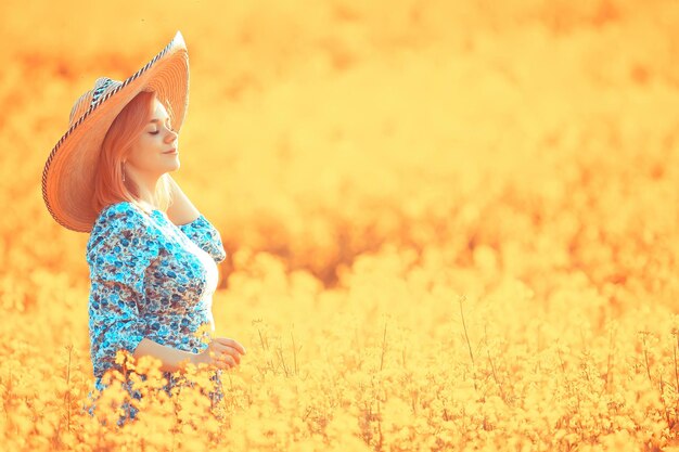 Mädchen in einem langen Vintage-Kleid-Hut in einem Blumenfeld, fröhliche Sommer-Sonnenfreiheit weiblich