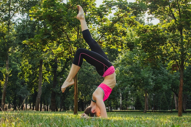 Mädchen in einem leichten Trainingsanzug, der nachmittags im Sommer Yoga im Park macht