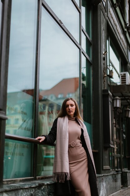 Mädchen in einem Mantel auf dem Hintergrund der Straßen der Stadt. Straßenfoto