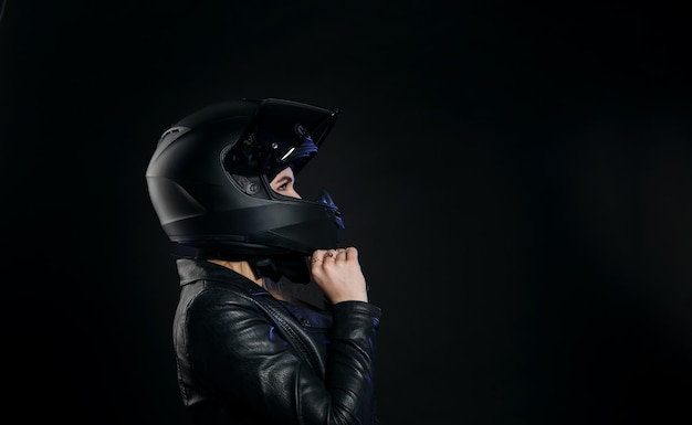 Mädchen in einem Motorradhelm und einer Lederjacke auf dunklem Hintergrund im Studio isoliert
