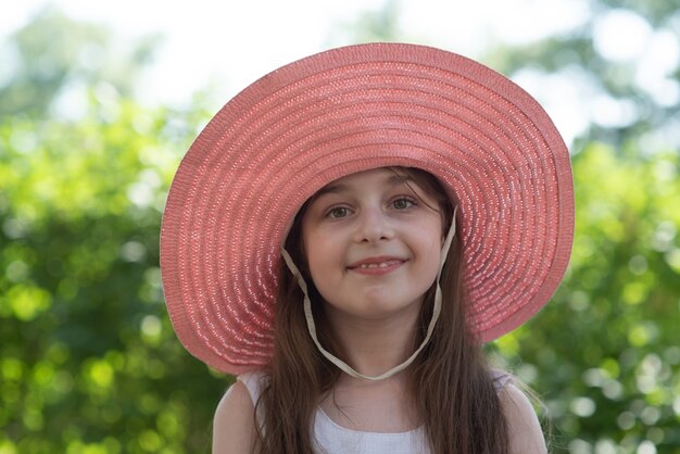 Mädchen in einem rosa Hut und einem weißen Kleid. Mädchen 9 Jahre alt im Sommer im Garten.