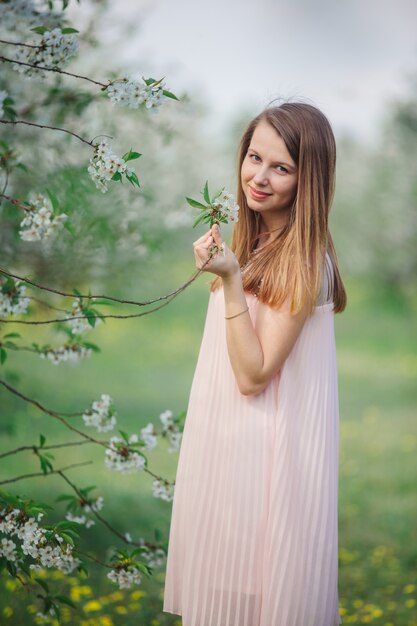 Mädchen in einem rosa Kleid in einem blühenden Garten