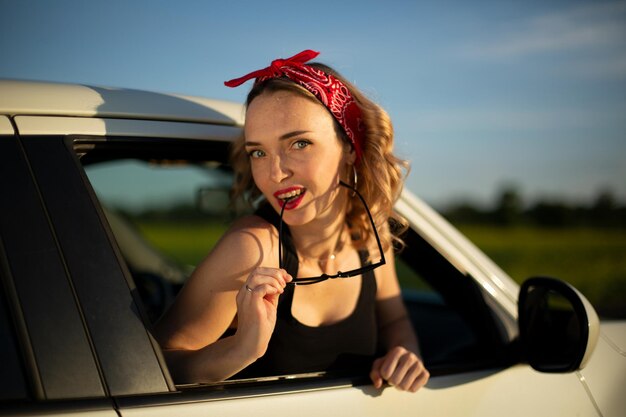 Mädchen in einem roten Kopftuch im Pinup-Stil im Auto