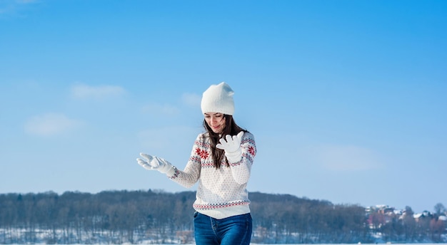 Mädchen in einem weißen Pullover auf schneebedecktem Eis des Sees im Winter
