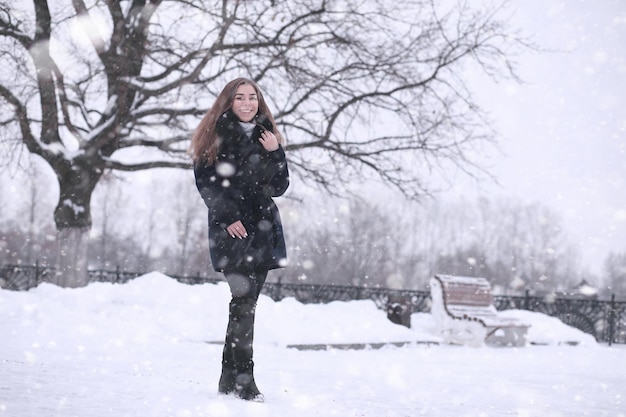 Mädchen in einem Winterpark am Nachmittag bei Schneefall