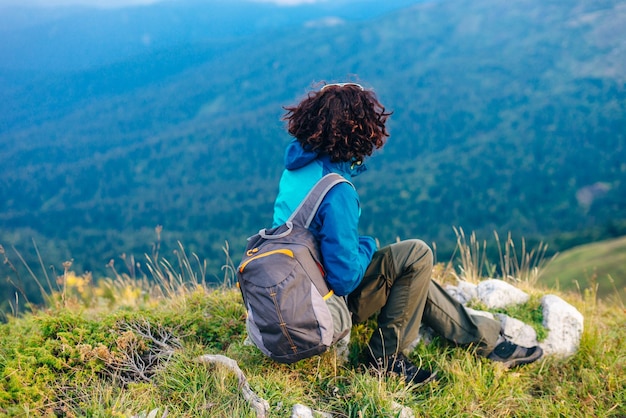 Mädchen in einer blauen Jacke mit Kapuze und einem Stadtrucksack im Adygea-Gebirge Russland