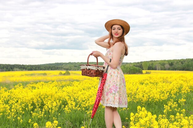 Mädchen in einer Blumenwiese mit Regenschirm und Hut