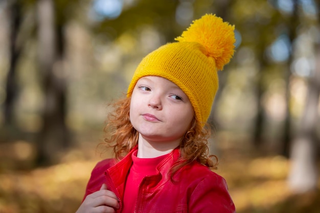 Mädchen in einer gelben Strickmütze im Herbst Porträt eines Kindes im Herbstpark