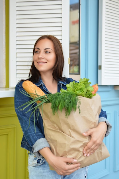 Mädchen in einer Jeansjacke hält eine Papiertüte mit Essen in ihren Händen