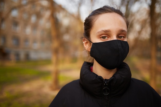 Mädchen in einer schwarzen medizinischen Maske auf der Straße Quarantäne Selbstisolierung