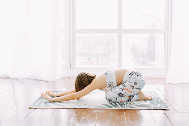 Mädchen in einer Sportuniform macht körperliche Übungen, Yoga und Dehnung zu Hause
