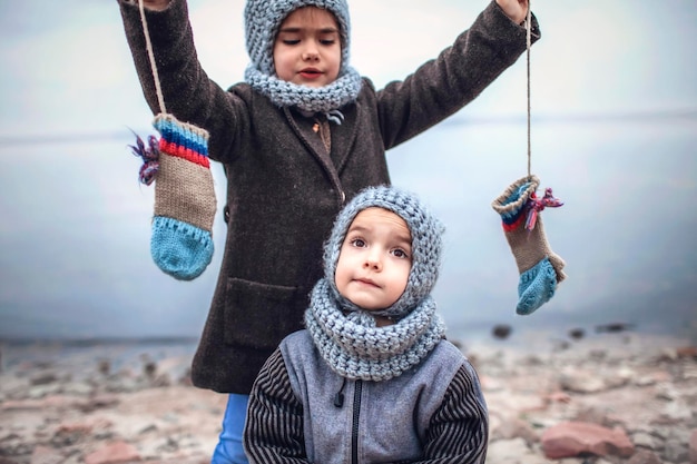 Foto mädchen in gestrickter grauer mütze, die handschuhe mit ihrem gefrorenen bruder teilt