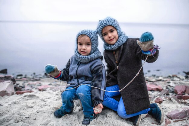 Mädchen in gestrickter grauer Mütze, die Handschuhe mit ihrem gefrorenen Bruder teilt