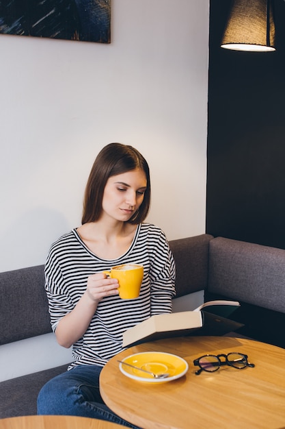 Mädchen in Gläsern ein Buch in einer Kaffeestube lesend