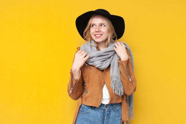 Mädchen in Herbstkleidung und Schal lächelt auf gelb isoliertem Hintergrund