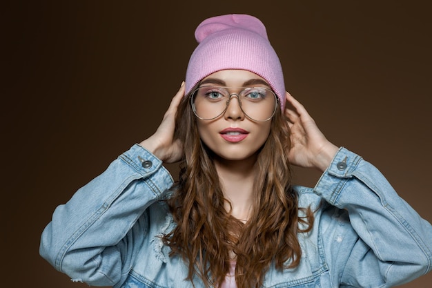 Mädchen in Jeansjacke, rosa Hut und stylischer Brille