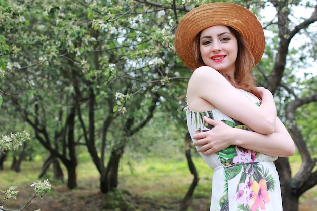 Mädchen in Kleid und Strohhut im Park